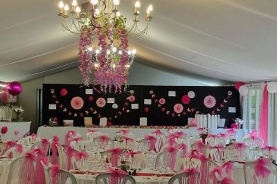 Deux tables rondes décorées pour un événement, avec nappes blanches, fleurs, verres et serviettes pliées.