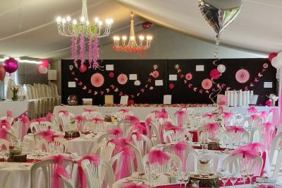 Deux tables rondes décorées pour un événement, avec nappes blanches, fleurs, verres et serviettes pliées.