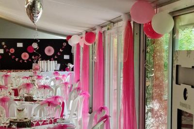 Deux tables rondes décorées pour un événement, avec nappes blanches, fleurs, verres et serviettes pliées.