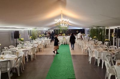 Deux tables rondes décorées pour un événement, avec nappes blanches, fleurs, verres et serviettes pliées.