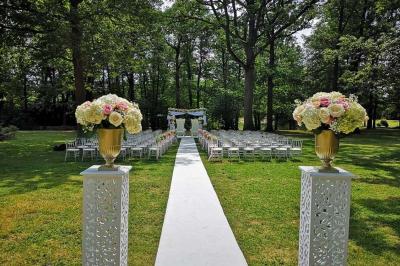 Deux tables rondes décorées pour un événement, avec nappes blanches, fleurs, verres et serviettes pliées.