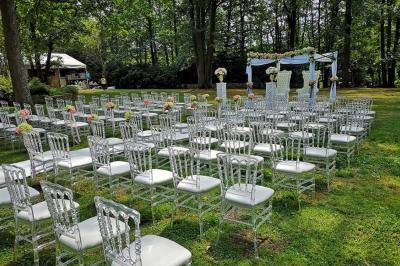 Deux tables rondes décorées pour un événement, avec nappes blanches, fleurs, verres et serviettes pliées.