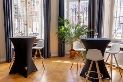 Couloir lumineux avec moquette verte, plantes en pot et portes blanches vitrées au fond.