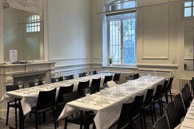 Couloir lumineux avec moquette verte, plantes en pot et portes blanches vitrées au fond.