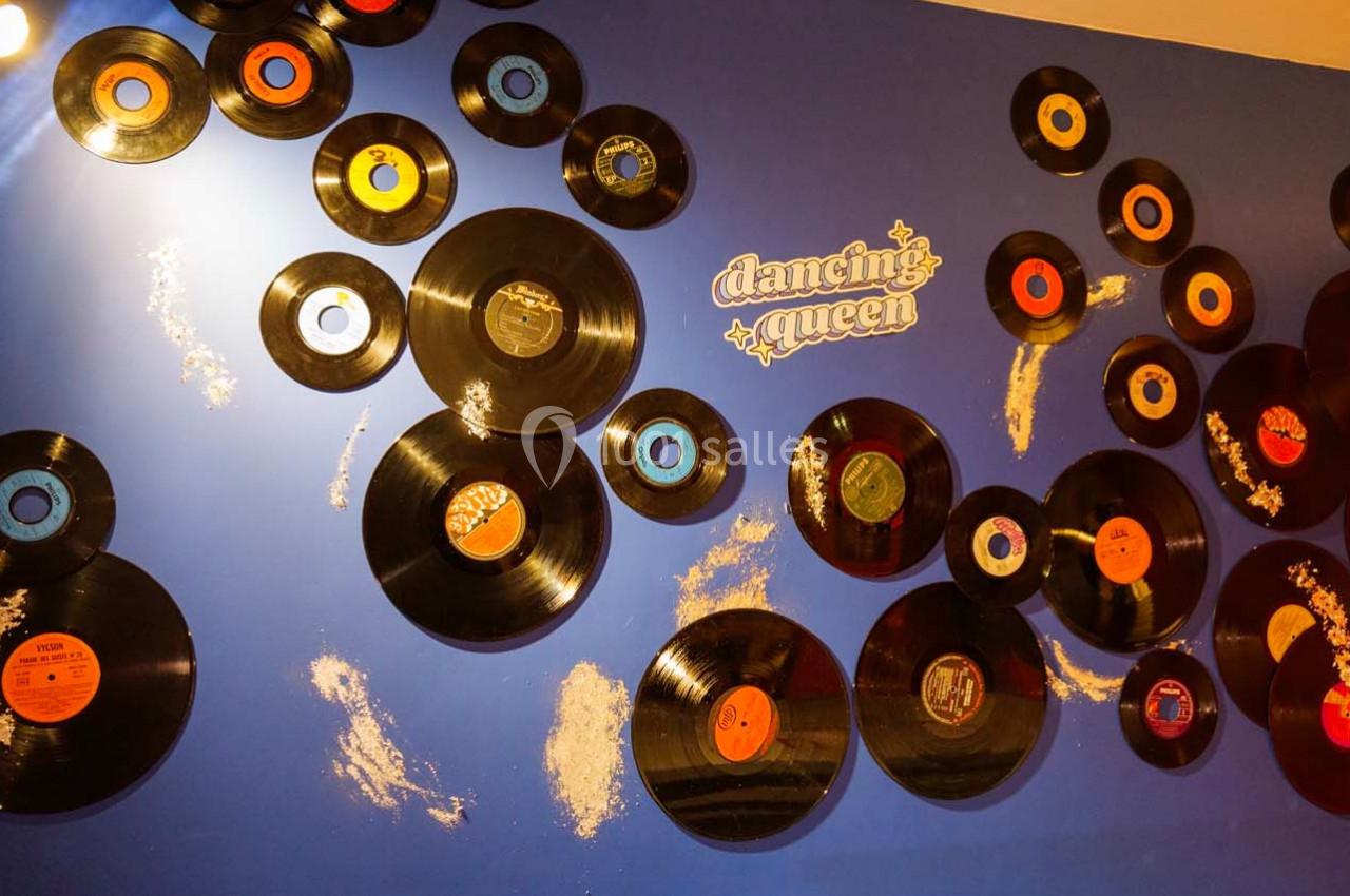 Disques vinyles accrochés sur un mur bleu avec l'inscription ’Dancing Queen’ en lettres blanches.