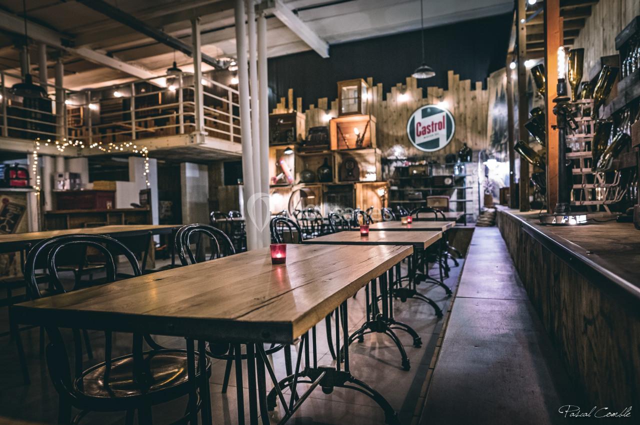 Salle de restaurant au style industriel avec tables en bois, chaises métalliques et décoration rétro.