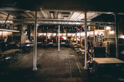 Un chandelier avec des bougies allumées posé près d'une ancienne presse métallique dans un décor artistique.