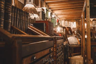 Un chandelier avec des bougies allumées posé près d'une ancienne presse métallique dans un décor artistique.