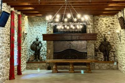 Château en pierre entouré d'arbres et de pelouses bien entretenues, avec un drapeau au sommet de la tour.