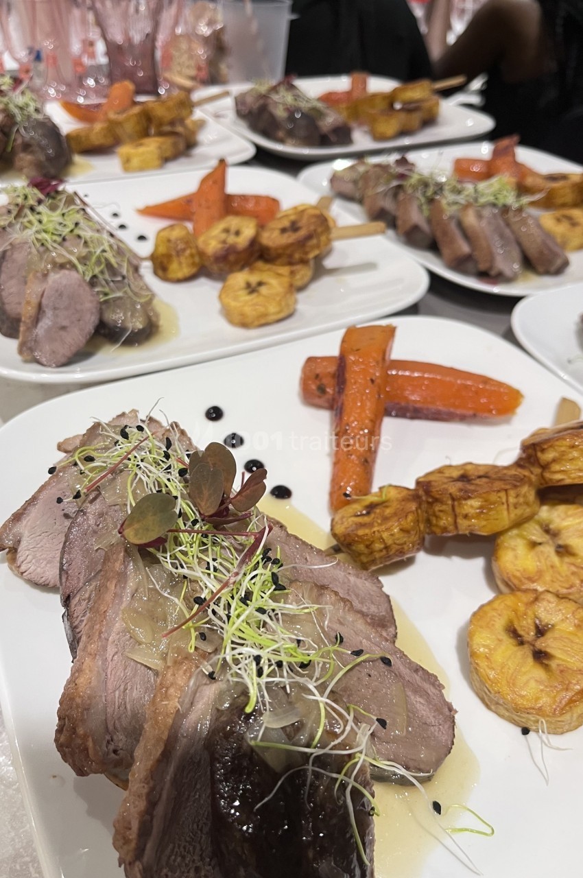 Assiettes de viande tranchée garnies de carottes, bananes plantains et pousses, servies avec une sauce.