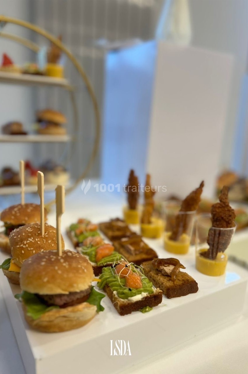 Plateau de mini-burgers, toasts garnis et verrines disposés sur une table pour un buffet ou un événement.