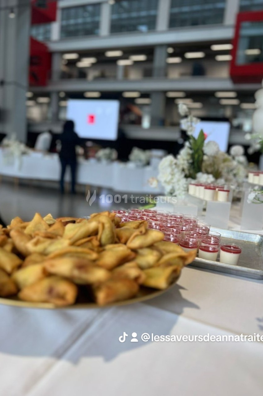 Assortiment de samoussas dorés et verrines disposés sur une table lors d'un événement dans un espace moderne.