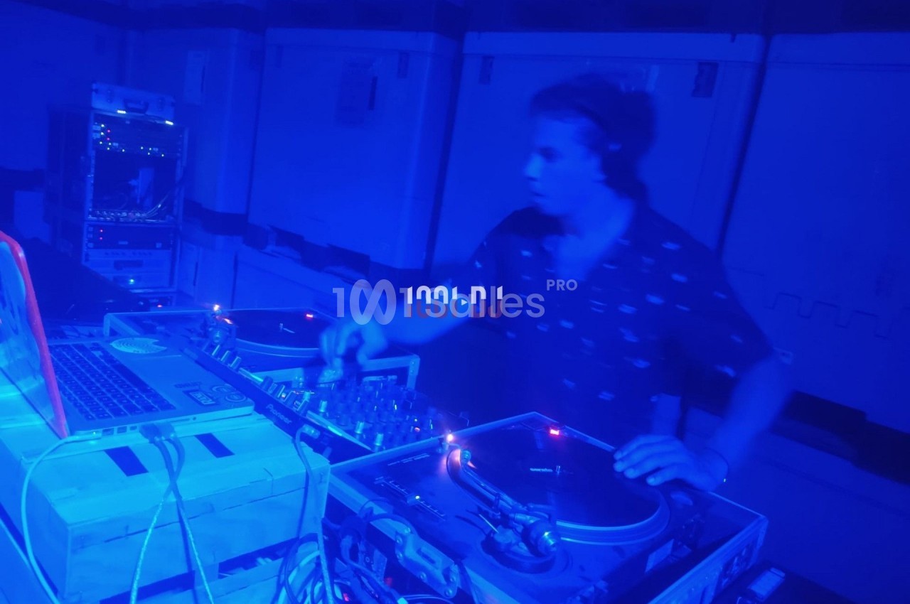Un DJ mixe de la musique sur des platines dans une ambiance lumineuse bleue.
