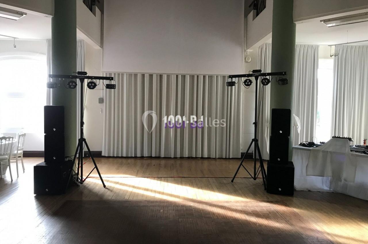 Installation de matériel de sonorisation et d'éclairage dans une salle lumineuse avec rideaux blancs.