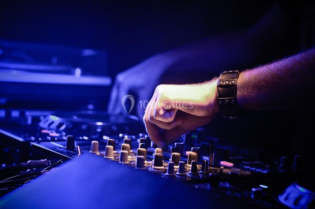 Main ajustant des commandes sur une table de mixage dans un environnement sombre.