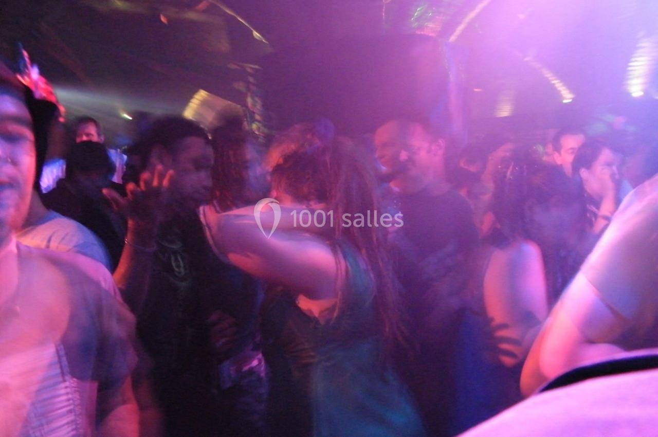 Groupe de personnes dans une ambiance festive et lumineuse avec éclairages colorés dans un espace sombre.