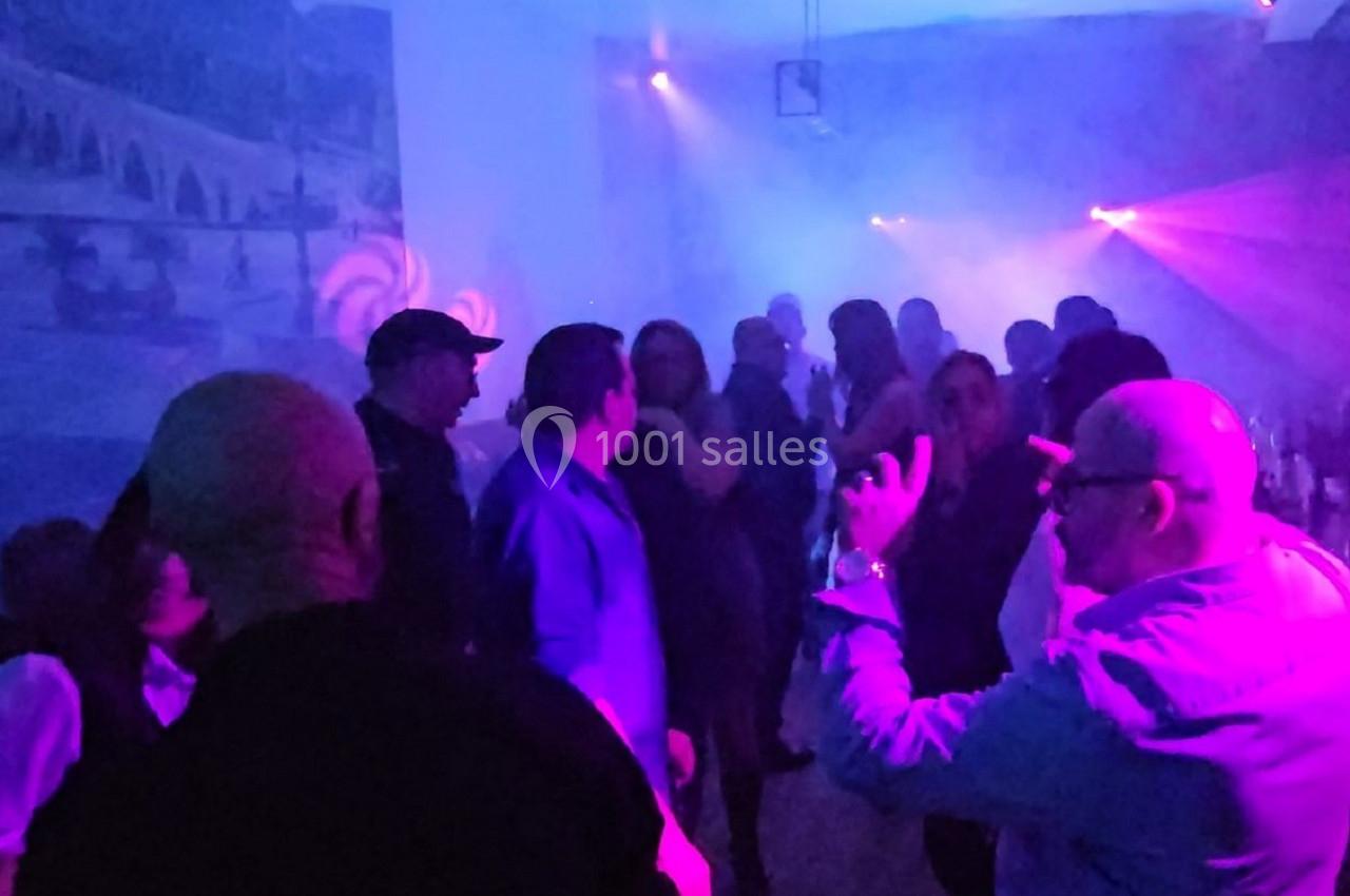 Groupe de personnes dans une ambiance festive avec éclairage coloré et fumée dans une salle.