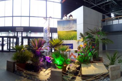 Stand d'exposition présentant des produits en béton, avec écrans, échantillons et décorations sur des tables.