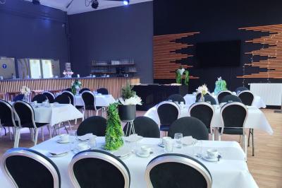 Salle de réception décorée avec des guirlandes lumineuses, tables dressées et éclairage tamisé bleu et rose.