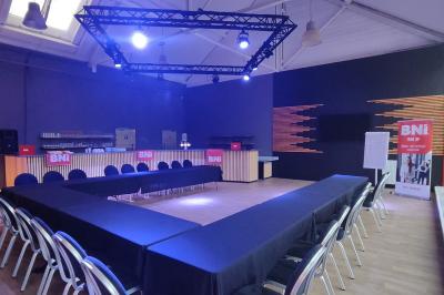 Salle de réception décorée avec des guirlandes lumineuses, tables dressées et éclairage tamisé bleu et rose.