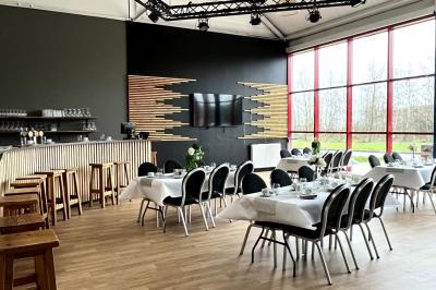 Salle de réception décorée avec des guirlandes lumineuses, tables dressées et éclairage tamisé bleu et rose.