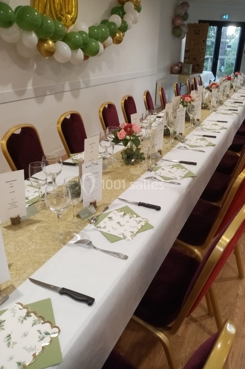 Table de réception élégamment dressée avec nappes blanches, décorations florales, menus et couverts alignés.