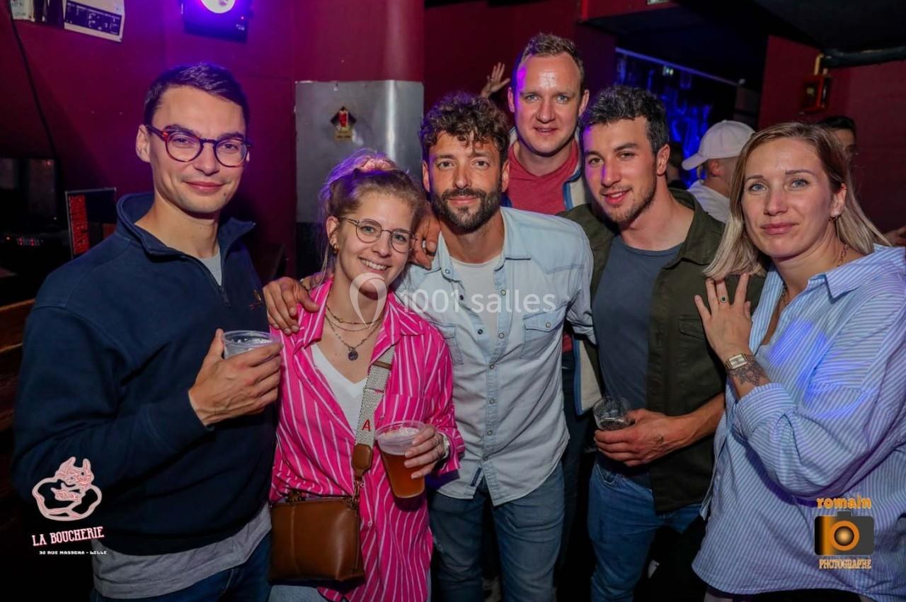 Un groupe de six personnes posant ensemble dans un bar, tenant des verres dans une ambiance festive.