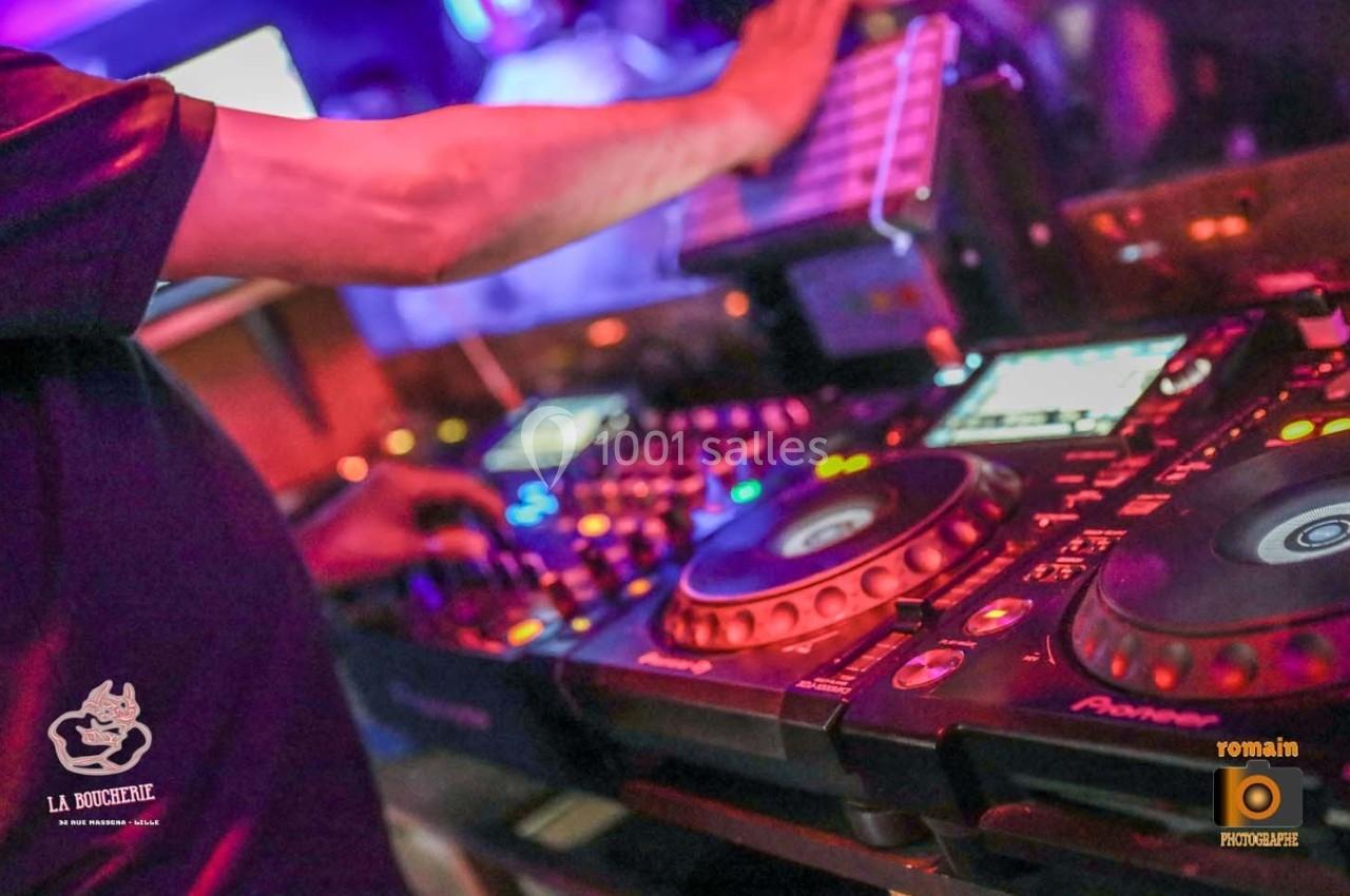 Un DJ mixant sur une table de mixage avec des lumières colorées en arrière-plan.