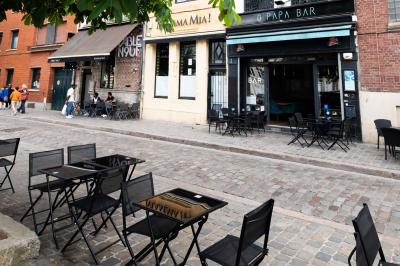 Miniature Location salle Lille (Nord) - O Papa Bar #19 Terrasse vide avec tables et chaises noires sur une rue pavée, devant des façades de cafés et restaurants.