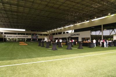 Table ronde en bois entourée de chaises à motifs rouges et blancs, située dans un jardin avec des plantes et des fleurs.