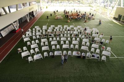 Table ronde en bois entourée de chaises à motifs rouges et blancs, située dans un jardin avec des plantes et des fleurs.