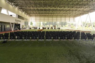 Table ronde en bois entourée de chaises à motifs rouges et blancs, située dans un jardin avec des plantes et des fleurs.
