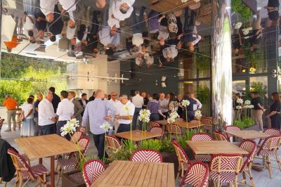 Table ronde en bois entourée de chaises à motifs rouges et blancs, située dans un jardin avec des plantes et des fleurs.