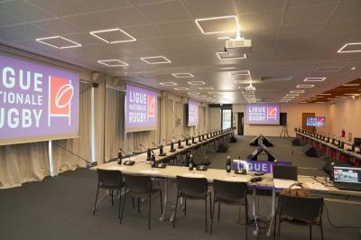 Table ronde en bois entourée de chaises à motifs rouges et blancs, située dans un jardin avec des plantes et des fleurs.