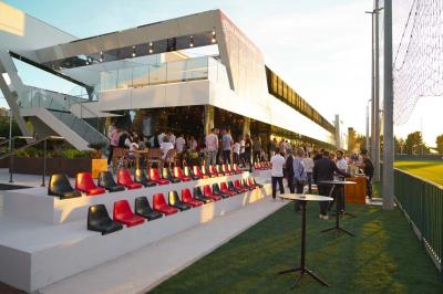 Table ronde en bois entourée de chaises à motifs rouges et blancs, située dans un jardin avec des plantes et des fleurs.