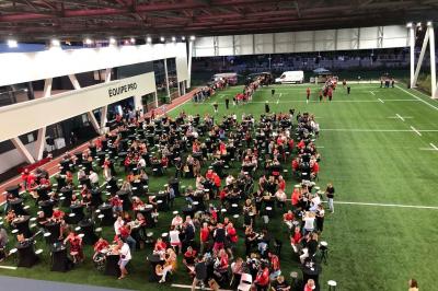 Table ronde en bois entourée de chaises à motifs rouges et blancs, située dans un jardin avec des plantes et des fleurs.