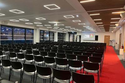 Table ronde en bois entourée de chaises à motifs rouges et blancs, située dans un jardin avec des plantes et des fleurs.