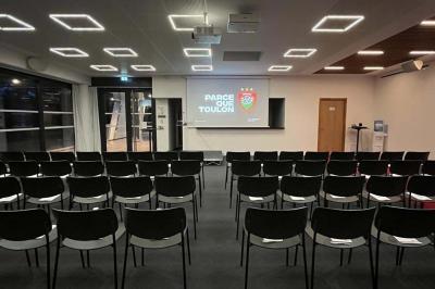 Table ronde en bois entourée de chaises à motifs rouges et blancs, située dans un jardin avec des plantes et des fleurs.