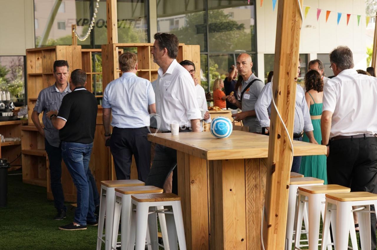 Des personnes discutent autour de tables en bois dans un espace intérieur lumineux avec des décorations festives.