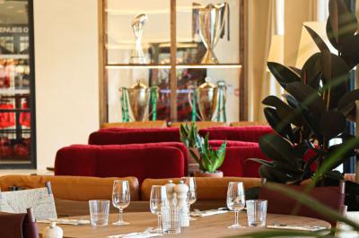 Table ronde en bois entourée de chaises à motifs rouges et blancs, située dans un jardin avec des plantes et des fleurs.