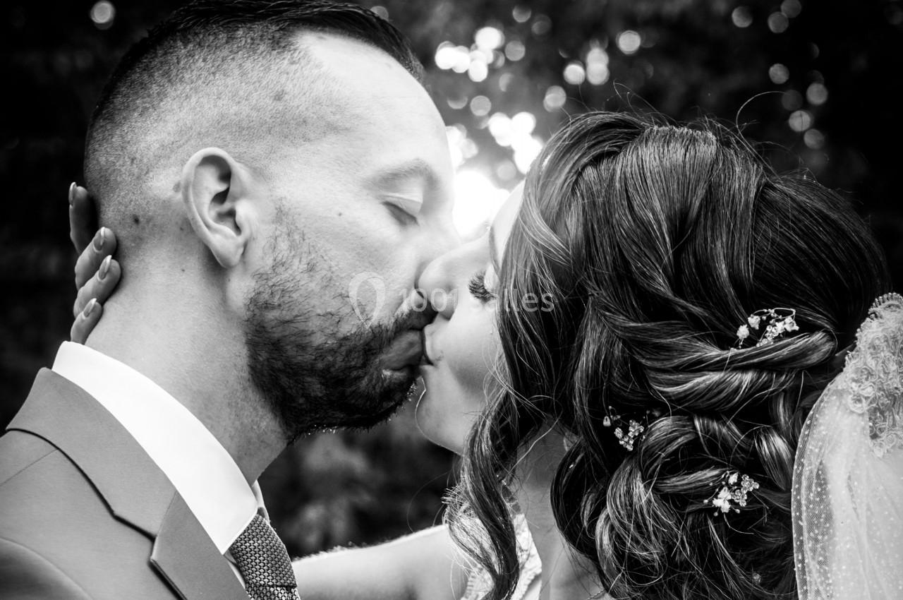 Un couple s'embrasse tendrement en gros plan, avec un arrière-plan flou et lumineux.