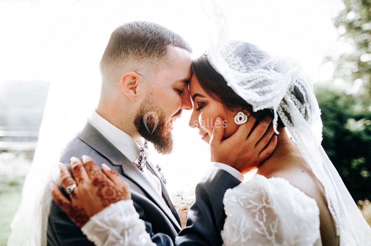 Un couple en tenue de mariage s'enlace tendrement en extérieur, éclairé par une lumière naturelle douce.