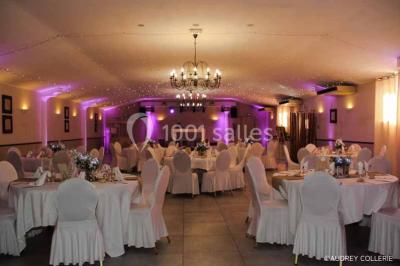 Un couple de mariés danse au centre d'une salle entourée d'invités, avec un sol recouvert de fumée légère.