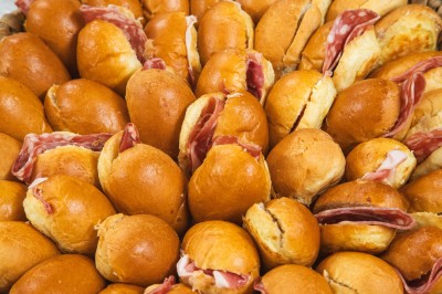Salle de réception décorée avec des tables rondes dressées, chaises rouges et plafond drapé de voilages lumineux.