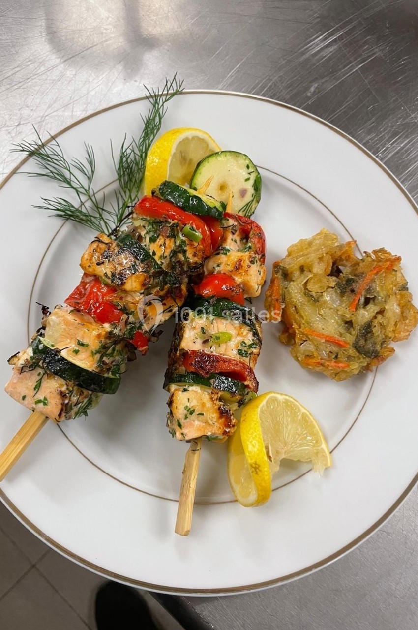 Brochettes de saumon grillé avec légumes, garnies de citron et d'aneth, accompagnées d'une galette de légumes.