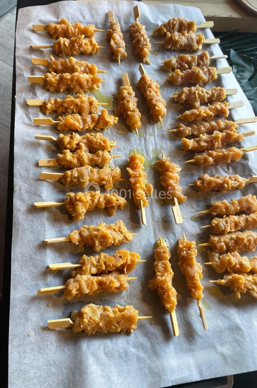 Brochettes de viande marinée alignées sur une plaque recouverte de papier sulfurisé, prêtes à être cuites.