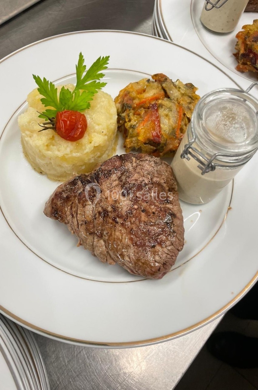 Assiette composée d'un steak grillé, d'une purée garnie, d'un gratin de légumes et d'une sauce en pot individuel.