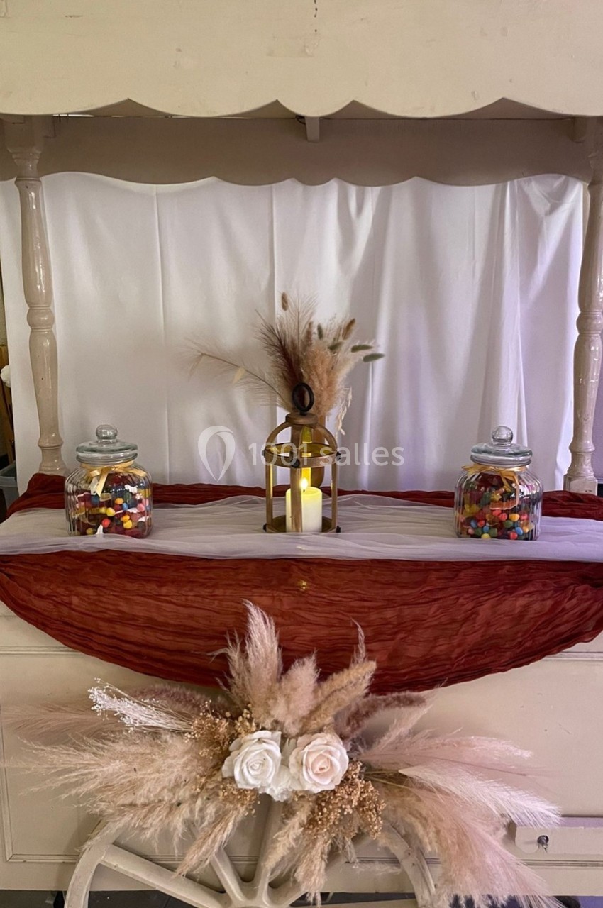 Chariot décoratif avec pots de bonbons, lanterne allumée et ornements de fleurs et d'herbes séchées.