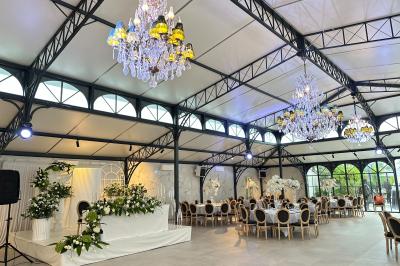 Terrasse extérieure avec tables, chaises, parasol, plantes et vue sur un bâtiment vitré sous un ciel dégagé.