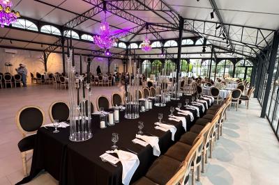 Terrasse extérieure avec tables, chaises, parasol, plantes et vue sur un bâtiment vitré sous un ciel dégagé.